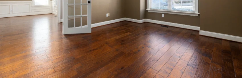 Dark hand-scraped hardwood floor in a sunlit room with a French door