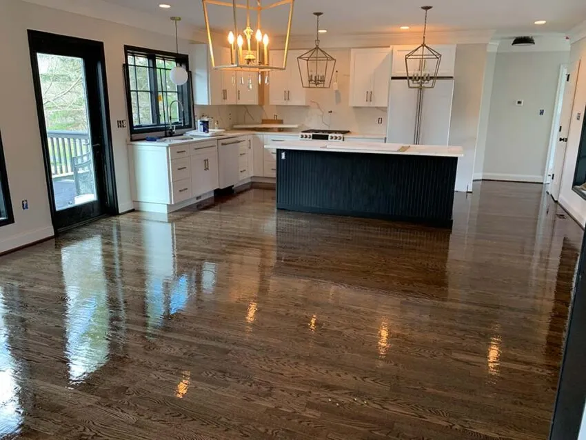 Bright, modern kitchen with white cabinets, a dark island, stainless appliances, and hardwood floors; glass doors open to an outdoor area.
