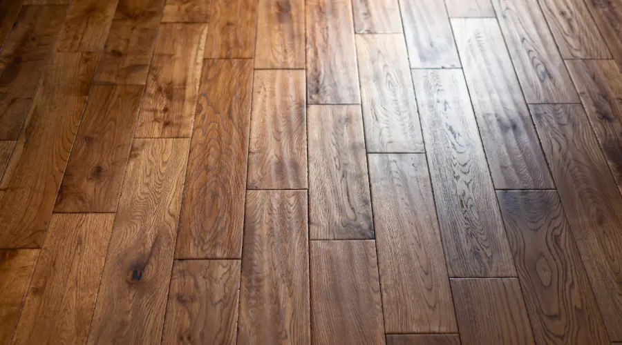 Wooden floor with wide brown planks and visible wood grain running lengthwise about a room corner.